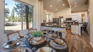 A dining area with a large window, a wooden table set for six, and a view of the outdoors.