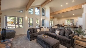 A spacious living room with a large sectional sofa, a wooden coffee table, and a stone fireplace.
