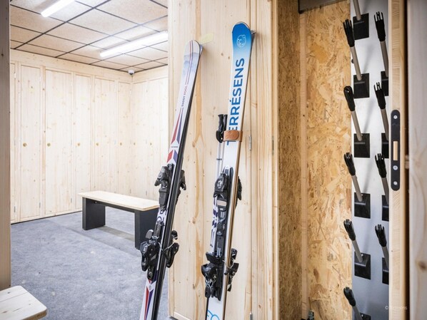 A wooden room with a bench, a pair of skis leaning against the wall, and a ski rack with multiple skis. - Apartment in Aime-la-plagne Near Fornelet Lift (Aime-la-Plagne)