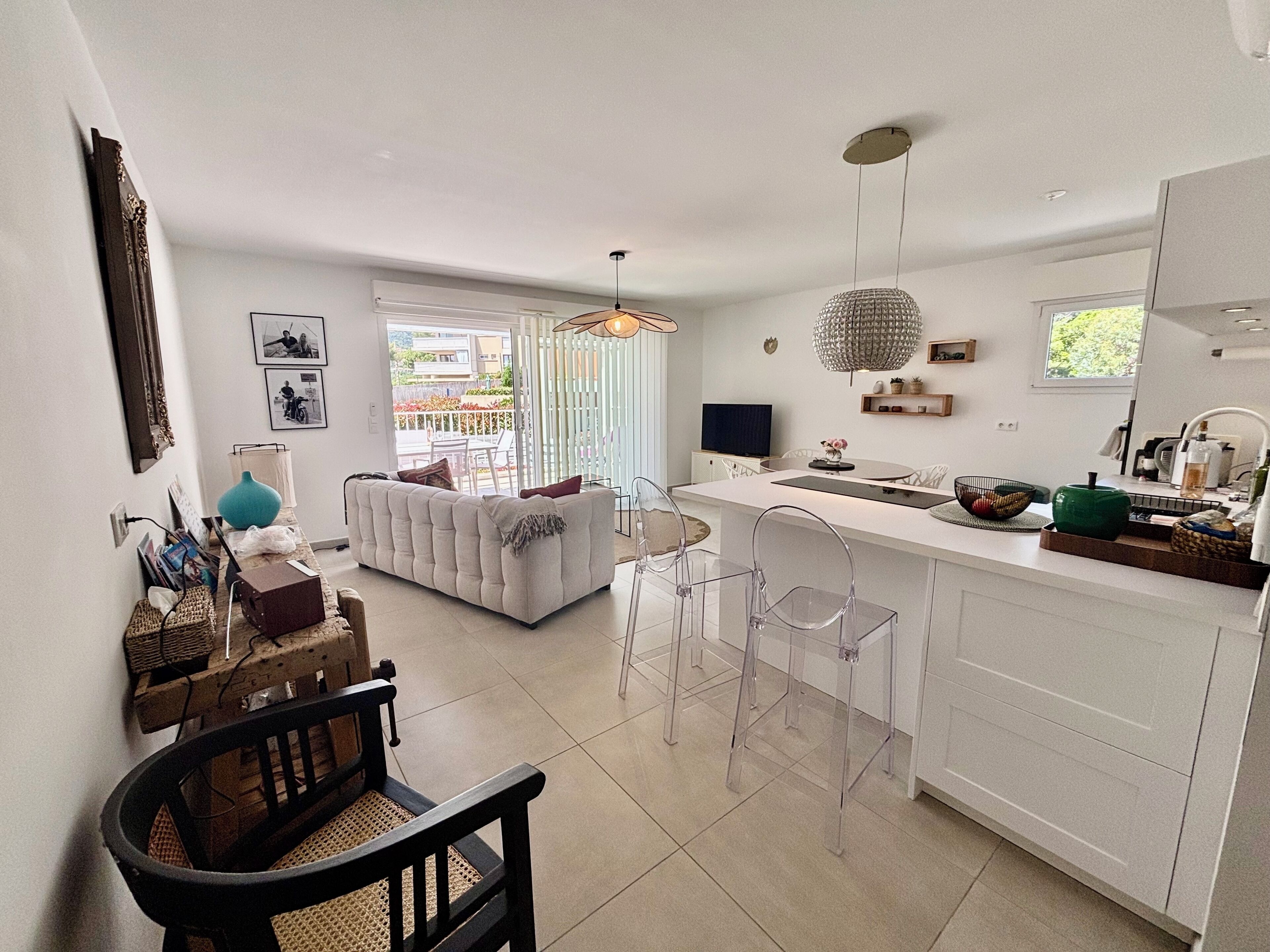A modern kitchen with a dining area, a sofa, and a TV.