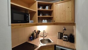 A compact kitchen with wooden cabinets, a microwave, a sink, and a toaster. - 200m from ski slopes, view ski slopes, swimming pool, sauna, tv, ski locker, 35m², Les Orres (Les Orres)