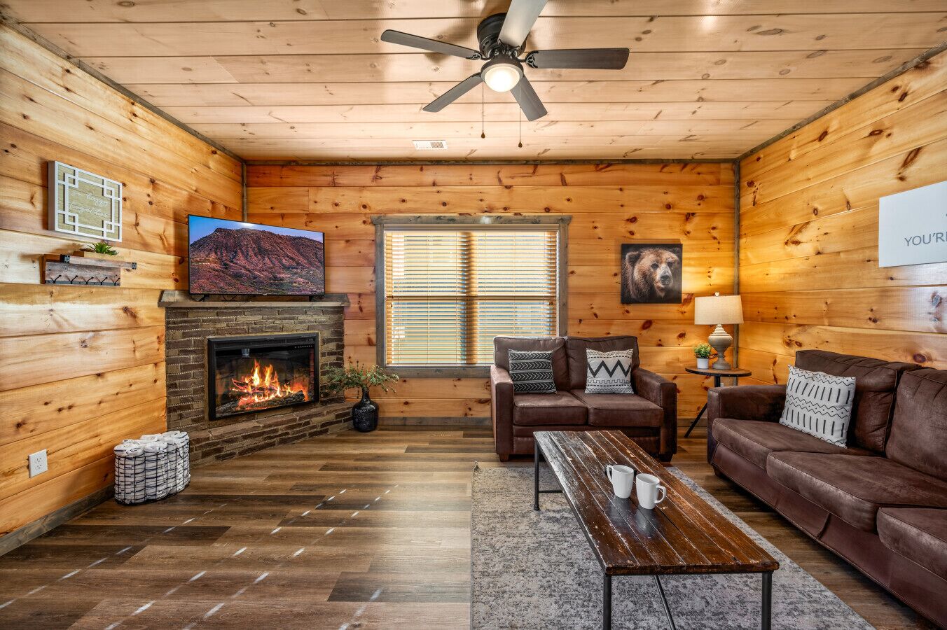 Ein gemütliches Blockhaus-Interieur mit Kamin, Holzwänden, einer Ledersofa und einem Fernseher.
