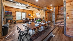 Ein Holzblockhaus-Interieur mit Essbereich, Kamin und einer Treppe.