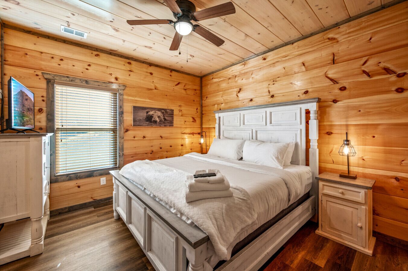 Ein Schlafzimmer einer Holzhütte mit Bett, Nachttisch und Deckenventilator.