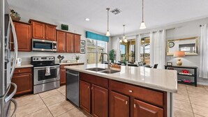 A modern kitchen with stainless steel appliances, wooden cabinets, and a large island.