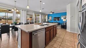 A modern kitchen with a large island, stainless steel appliances, and a blue accent wall.