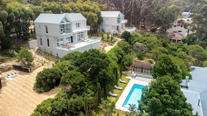 Une maison moderne à deux étages, dotée d’un grand jardin, d’une piscine et d’une pergola.