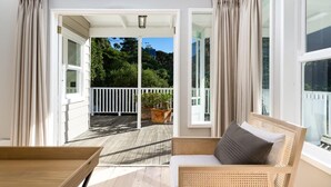 Un balcon doté d'un plancher en bois, d'un canapé en osier et d'une plante en pot.