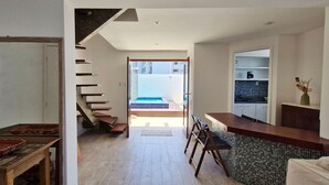 A modern kitchen with a bar area, a staircase leading to an outdoor balcony, and a dining area with a wooden table and chairs. - COBAR0130 - Edifício Porto do Sol (Salvador)