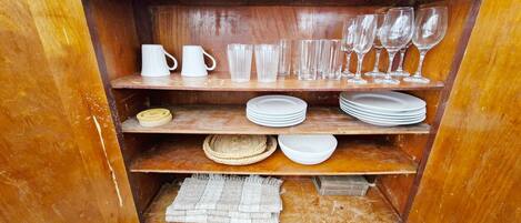 A wooden shelf unit with various glassware and plates.