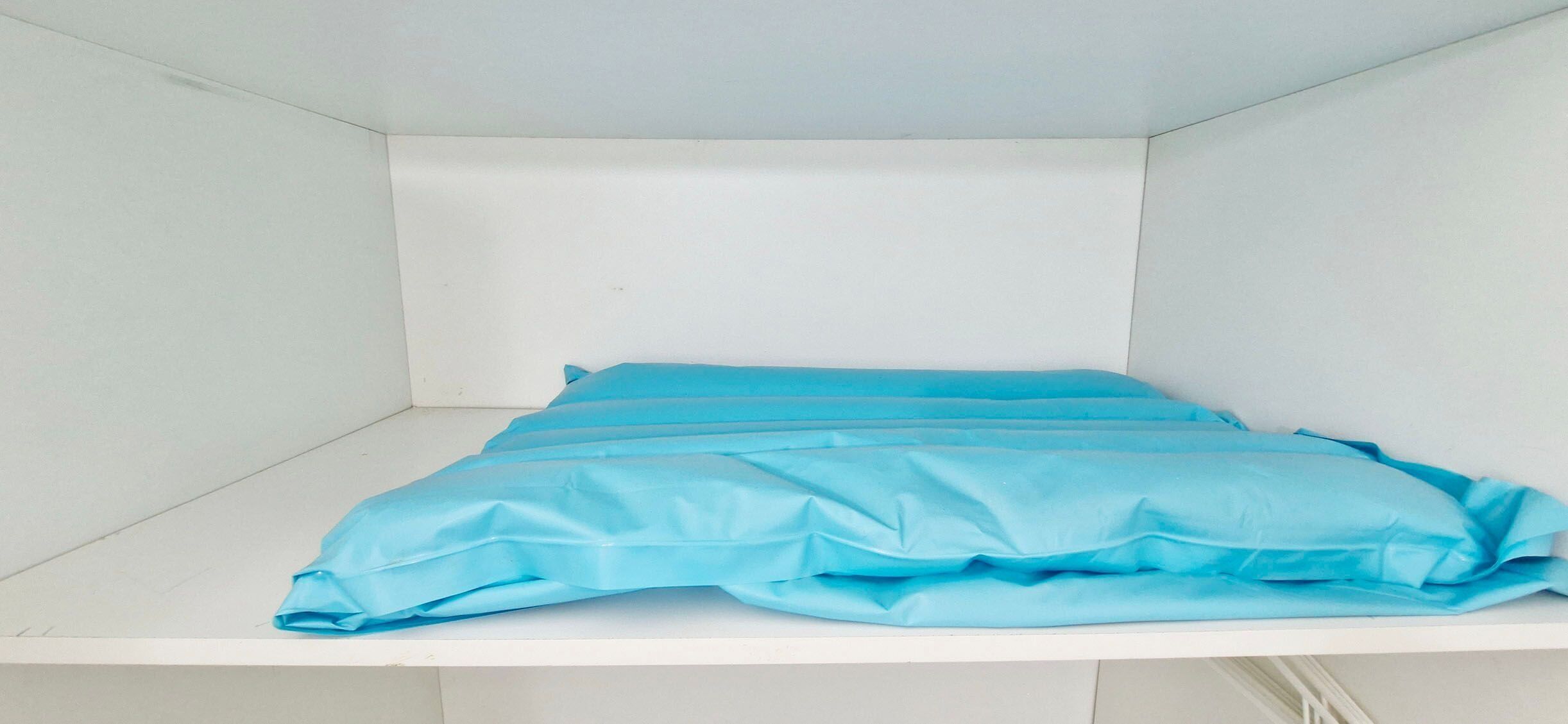 A bed with a blue cover in a white room.