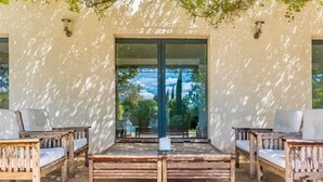 A patio area with wooden benches and a glass door leading to an interior space. - Villa Aix-en-Provence Piscine et calme absolu (paris)