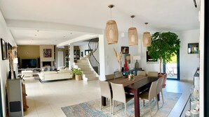 A spacious living area with a dining table, chairs, and hanging wicker lights. - Villa Aix-en-Provence Piscine et calme absolu (paris)