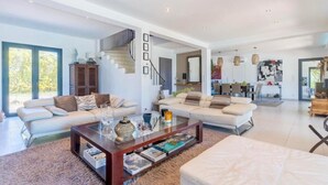 A spacious living area with a large sofa, a coffee table, and a staircase leading to an upper floor. - Villa Aix-en-Provence Piscine et calme absolu (paris)