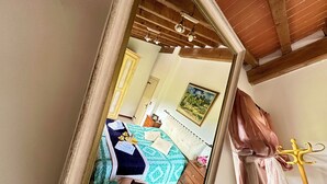 A bedroom with a bed, a wooden chair, a mirror, a wooden ceiling, and a painting on the wall. - Milu's Holiday Home (Toscana)