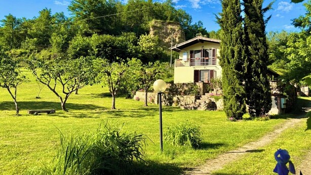 A two-story house with a stone facade, surrounded by lush greenery and trees. - Milu's Holiday Home (Toscana)