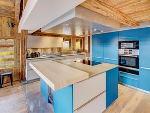 Uma cozinha moderna com ilha central, armários azuis e detalhes em madeira.