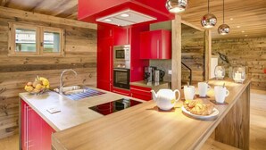 Cocina moderna con armarios rojos, una isla central y electrodomésticos de acero inoxidable.