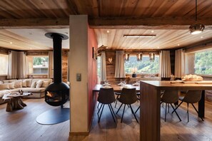 A cozy interior with a fireplace, wooden furniture, and a dining area with a view of the outdoors.