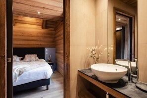 A wooden interior with a bed, a large white sink, and a mirror.