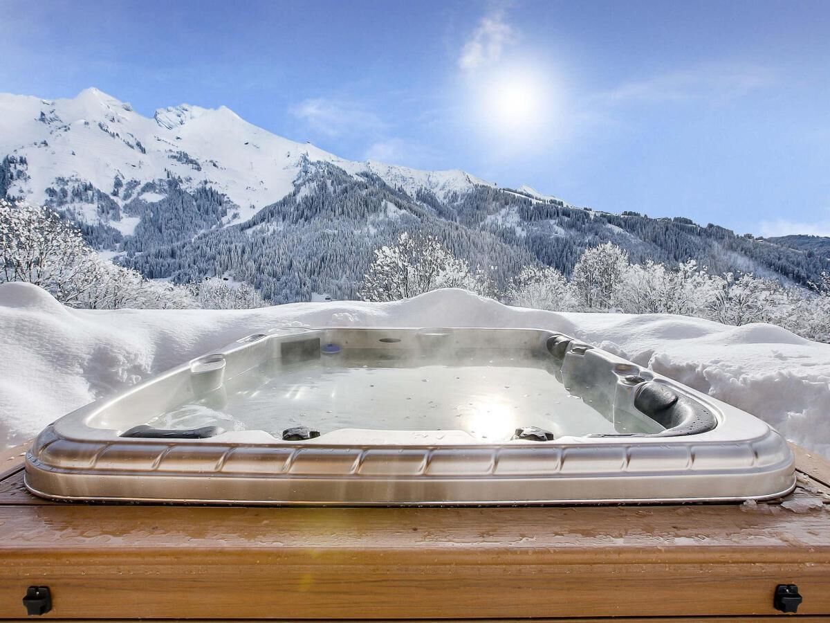 A hot tub on a wooden platform with a snowy mountain backdrop.