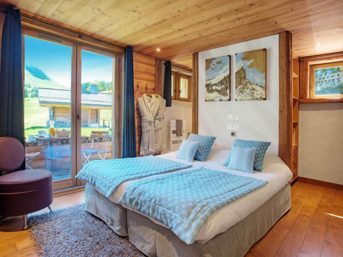 A bedroom with two beds, a large window, and a view of a mountain.