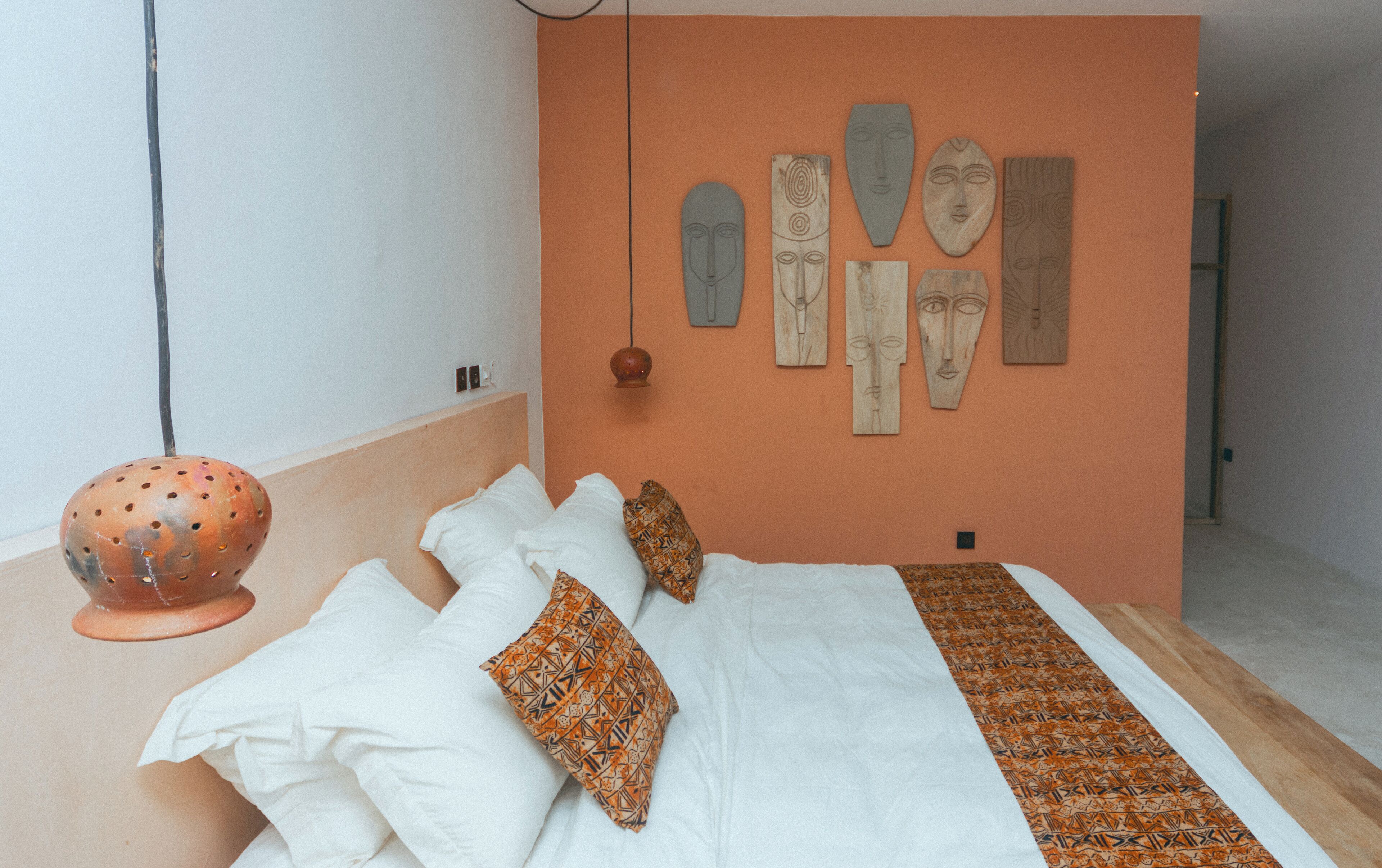 A bedroom with a bed, pillows, and a wall decorated with wooden art pieces.