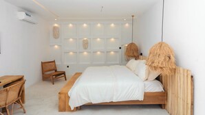 Une chambre à coucher au style minimaliste, avec un lit en bois, un bureau et des chaises en osier.