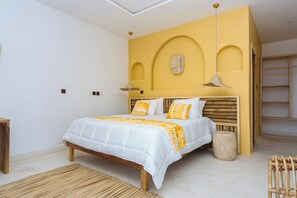 A bedroom with a bed, wooden headboard, and a yellow accent wall. - MIADJOE BEACH RESORT (Aného)