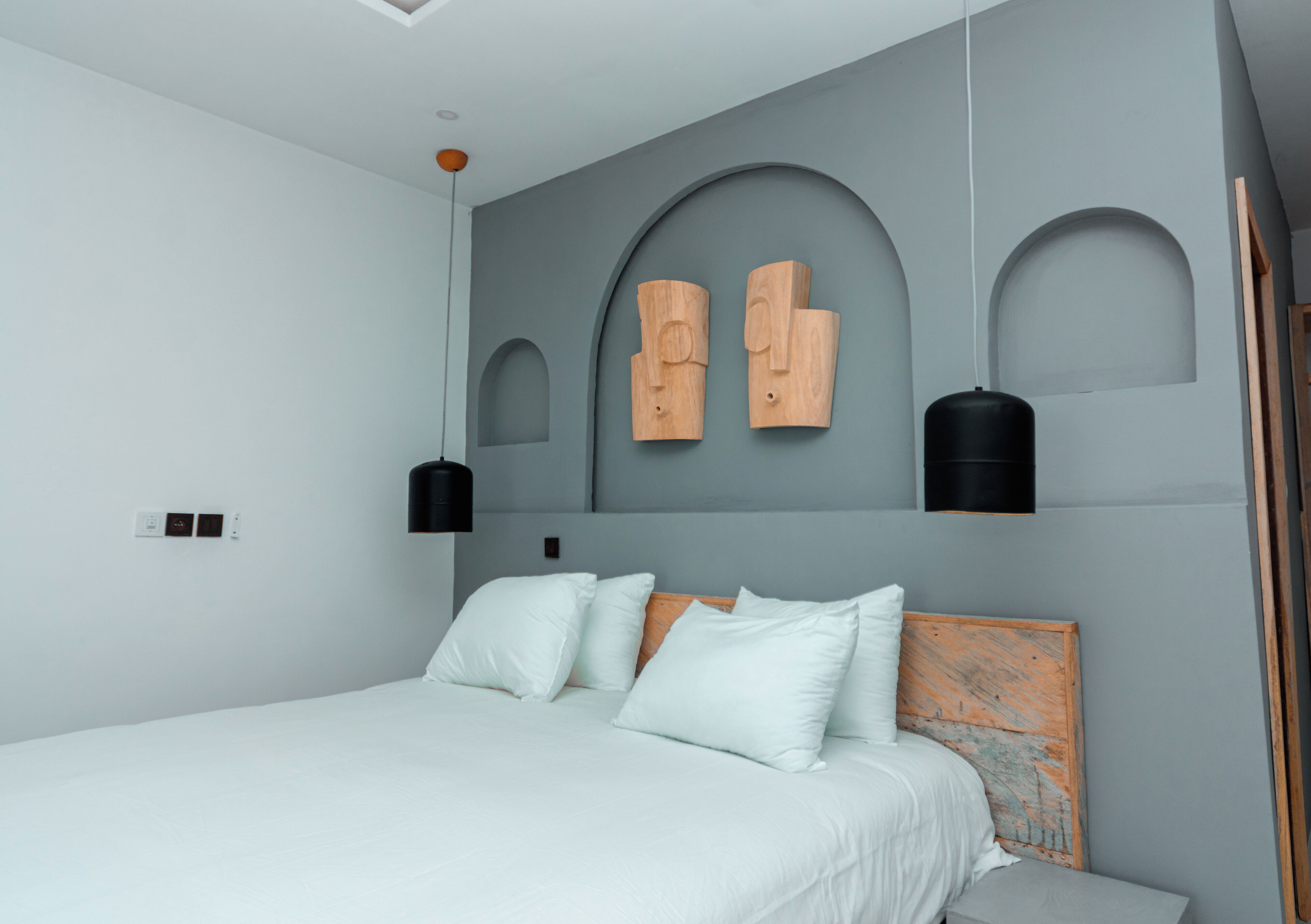 A modern bedroom with a large bed, a wooden headboard, and a unique wall design with geometric shapes.