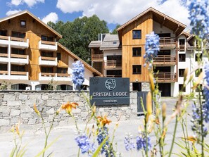 Ein Schild für Cristal Lodge, im Hintergrund eine Steinmauer und Holzhäuser.