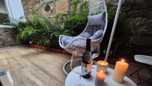 Un espacio al aire libre acogedor con una mesa redonda, un sillón colgante y velas.