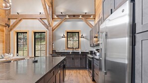 A modern kitchen with dark cabinetry, stainless steel appliances, and a large island.