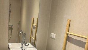 A bathroom with a white sink, a mirror, and a bamboo towel rack.