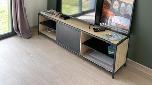 A modern room with a large window, a flat-screen TV, a poster, and a wooden entertainment unit.