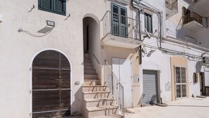 A building with a staircase, a large metal gate, and a balcony with railings. - Il Faro by BarbarHouse (Vieste)