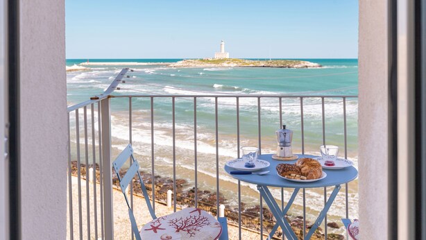 A balcony with a table set for breakfast overlooking the sea, featuring a lighthouse in the distance. - Il Faro by BarbarHouse (Vieste)