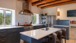 A modern kitchen with a central island, dark cabinetry, and a large window offering a view of the outdoors.