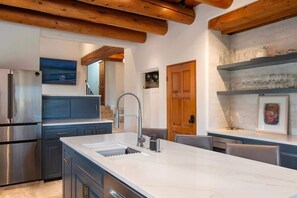 Una cocina moderna con una isla de mármol, electrodomésticos de acero inoxidable y vigas de madera.