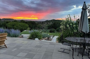 Un patio con vistas a la puesta de sol, una silla de madera y una mesa con sillas.