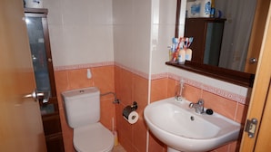 A bathroom with a toilet, sink, and a mirror. - noo............................. (Sant Antoni de Calonge)