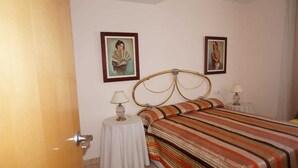 A bedroom with a bed, two bedside tables with lamps, and two framed pictures on the wall. - noo............................. (Sant Antoni de Calonge)