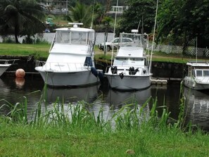 Twee boten aangemeerd in een jachthaven, met een grasveld op de voorgrond en een weg op de achtergrond.