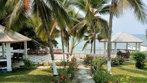 Un resort con un espacio de estar al aire libre cubierto, un camino y vista al mar.