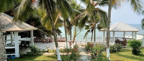 A resort with a covered outdoor seating area, a pathway, and a view of the sea.