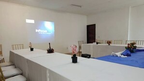 Een vergaderruimte met een lange tafel, stoelen en een projectiescherm waarop 'InFocus' staat.