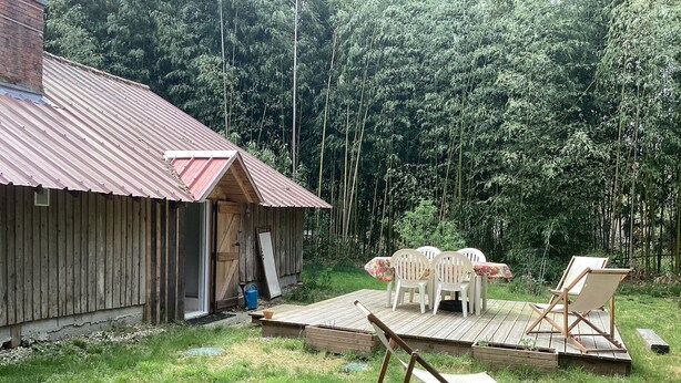 A rustic wooden building with a metal roof, a small deck, and a table with chairs. - Charming cabin by a lake in the heart of the Landes d'Armagnac forest (Losse)