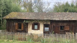 A rustic wooden house with a tiled roof, surrounded by a wooden fence and greenery. - Charming cabin by a lake in the heart of the Landes d'Armagnac forest (Losse)