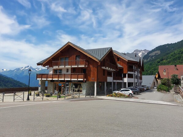 Un edificio de madera con balcones, un letrero que dice 'Atou Sport' y una vista de la montaña al fondo.