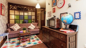 Una sala de estar acogedora con un sofá a rayas, un mueble de madera, un globo terráqueo y un televisor.